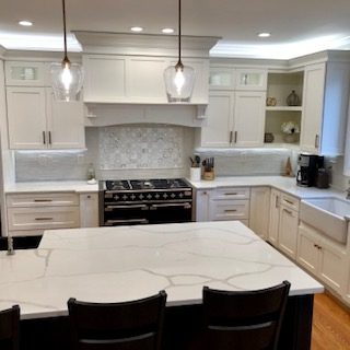 A kitchen with white cabinets and black chairs.