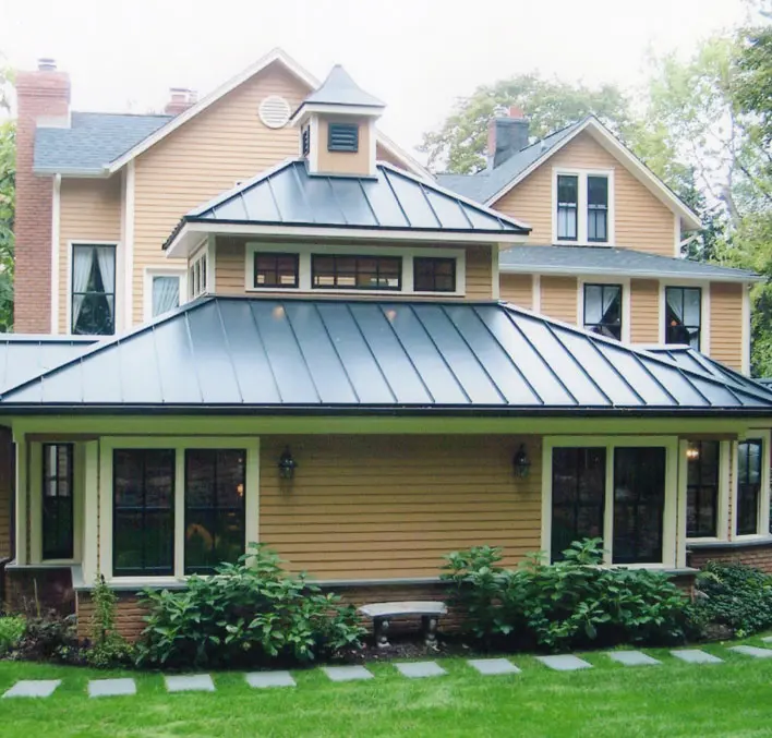 A yellow house with a black roof and green trim.