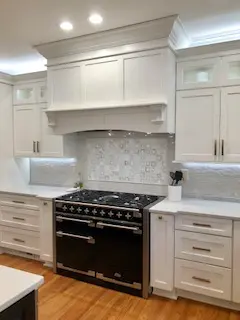A kitchen with white cabinets and black stove.