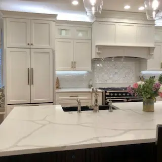A kitchen with white cabinets and marble countertops.