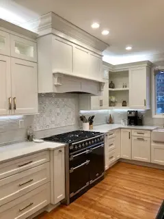 A kitchen with white cabinets and black oven.