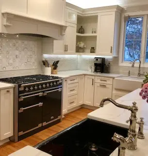 A kitchen with white cabinets and black stove.